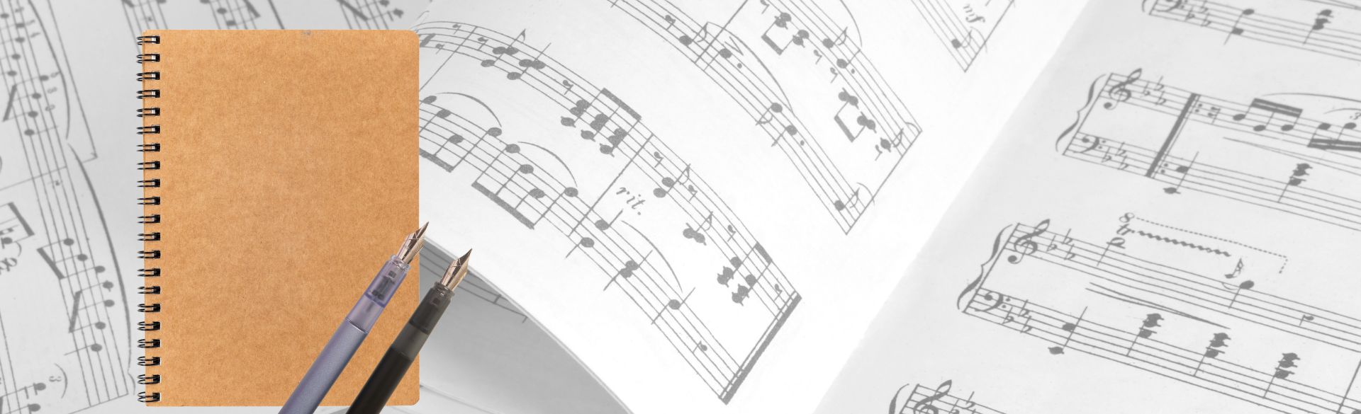 Man sieht Notenblätter mit Notizbuch und Füller